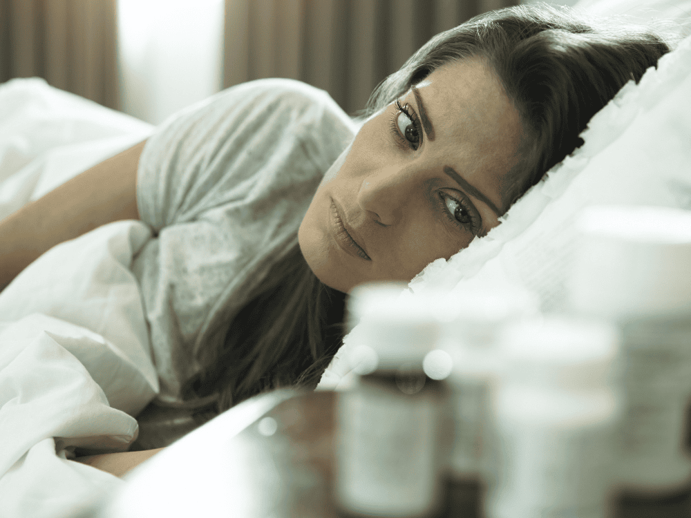 A woman with ADHD looking unhappily at her medication wondering about TMS vs. Adderall