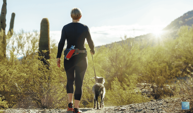 A woman considering depression treatments in Scottsdale, AZ while walking a dog in the desert.